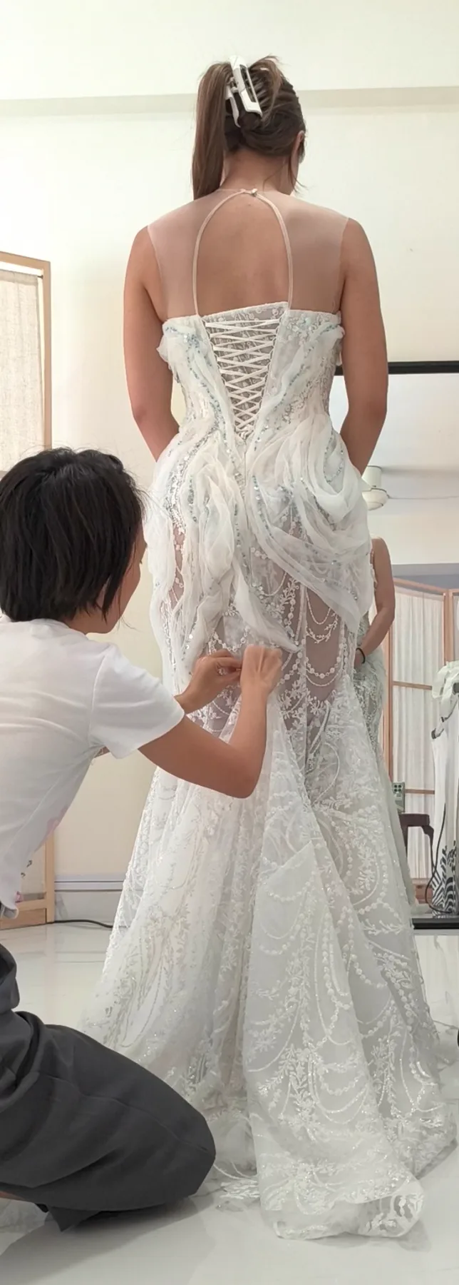 Hui Ling pinning the back panel of an embellished gown during a private fitting